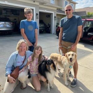 Parents and their two children posing with their new golden retriever and collie.