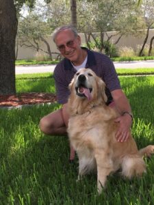 Senior golden with adopter on grassy yard.